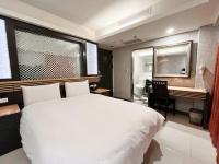 a bedroom with a large white bed and a desk at Guide Hotel Taipei Xinyi in Taipei