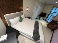 a bedroom with a bed with white sheets and a chair at Boston Hotel in Chiayi City