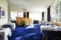 Un restaurante con mesas y sillas blancas y ventanas. en Hotel Meerane, en Meerane