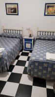 two beds in a room with a checkered floor at Pensión San Benito Abad in Seville