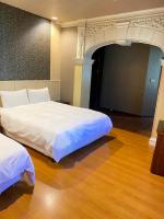 a bedroom with two beds in a room with wood floors at The Prince Hotel in Tainan