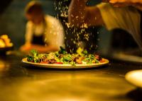 a person is making a pizza on a table at Holiday Club Åre in Åre