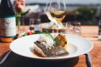 un plato de comida en una mesa con copas de vino en Slottsholmen Hotell och Restaurang, en Västervik