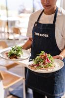 un hombre sosteniendo dos platos de comida en un mostrador en Seafront Hotel Kangaroo Island, en Penneshaw