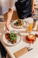 una persona parada en una mesa con dos platos de comida en Seafront Hotel Kangaroo Island, en Penneshaw