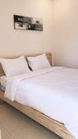 Dos camas en una habitación con sábanas y almohadas blancas. en A-Manta Homestay, en Labuan Bajo