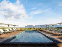 a pool with lounge chairs and the ocean in the background at ibis Styles Porto Vecchio in Porto-Vecchio