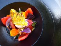 a black plate of food with an egg and vegetables at Auberge Les Grillons in Meyras