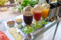 three glasses of different colored drinks on a glass table at Pousada Boulevard in Cabo Frio