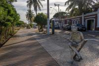 a statue of a man sitting on a bench on a sidewalk at Pousada Boulevard in Cabo Frio