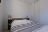 a bed in a bedroom with a white wall at LaConciergerieJonzac, Appartement La Désirade in Jonzac