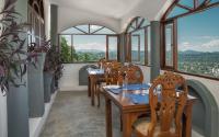 Un restaurante con mesas y sillas de madera y ventanas. en Ceylon Breeze, en Kandy
