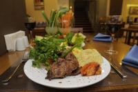 Un plato de comida con carne y verduras en una mesa. en Sahil Hotel Pendik, en Tuzla