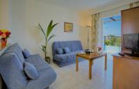 a living room with a blue couch and a tv at Corali Hotel in Tigaki