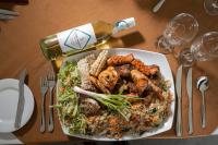 a plate of food with a salad and a bottle of wine at Rajarata Hotel Anuradhapura in Anuradhapura