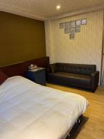 a bedroom with a bed and a leather couch at 橙橙民宿 in Ruifang