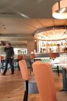 Un restaurante con sillas y mesas naranjas y un bar. en Mage hôtels - HÔTEL LA GRENETTE, en Roanne