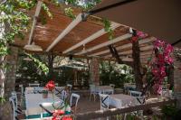 Un patio con mesas y sillas bajo una pérgola de madera. en Soleil Village & Villas, en Jal