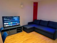 a living room with a blue couch and a flat screen tv at Maison Climatisée 04 chambres Paris Disney CDG in Gagny