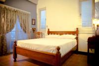 a bedroom with a bed with white sheets and windows at Alongs Garden in Hengchun South Gate
