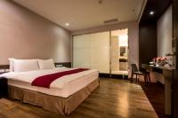 a bedroom with a large bed and a desk with a chair at Chateau-Rich Hotel in Tainan