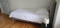 a bed with white sheets and a roll of toilet paper on a table at Résidence Auger in Bourges