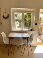 a dining room table with white chairs and a window at Appartement duplex in Le Touquet-Paris-Plage
