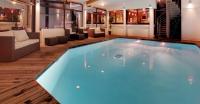 a swimming pool in a hotel room with a couch and chairs at Hotel Le Panorama in Le Mont-Dore