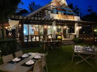 Un restaurante con mesas y sillas frente a un edificio. en Infinity Diving Resort and Residences, en Dauin