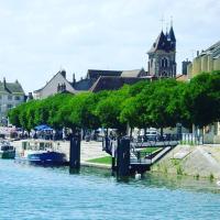 a river with boats docked next to a church at Les sorciers, la Diligence St Jean de Losne in Saint-Jean-de-Losne