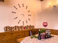 Un reloj en la pared con copas de vino y una mesa. en Hotel da Beppe Sello, en Cortina dʼAmpezzo