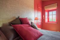 a bedroom with red walls and a couch with red pillows at Chez Joseph - Au coeur des vignes de Saint-Romain in Saint-Romain