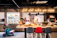 a bakery with a counter with colorful chairs at Moxy The Hague in The Hague
