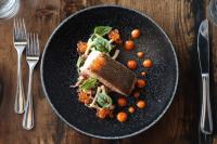 a black plate with a sandwich and tomatoes on a table at Stunning Stayz At Friday Harbour Beach Marina Resort Lake Simcoe Innisfil in Innisfil