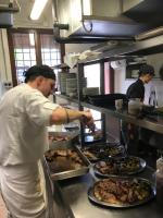 Een man die eten klaarmaakt in een keuken met borden. bij Relais Ca del rio in Botteghino di Zocca