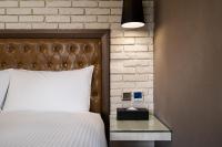 a bedroom with a white bed and a brick wall at The Cloud Hotel in Kaohsiung