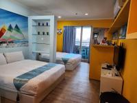 a bedroom with two beds and a television in it at MB Hotel in Kaohsiung