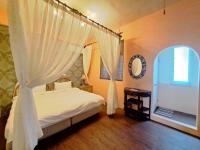 a bedroom with a bed with white curtains and a window at Bellalia 貝拉利亞 花蓮民宿 in Hualien City