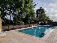 ein Schwimmbad in einem Garten neben einem Zaun in der Unterkunft Hotel Landhuis &#39;t Wilgenerf in Ypern