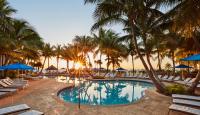 ein Resortpool mit Stühlen und Palmen bei Sonnenuntergang in der Unterkunft Cheeca Lodge &amp; Spa in Islamorada