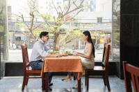 Un hombre y una mujer sentados en una mesa comiendo comida en Hotel Soco, en Da Nang
