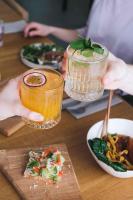 KODAS Hubane iglumajutus järve kaldal في Valgjärve: شخص يحمل مشروبًا على طاولة مع أطباق الطعام