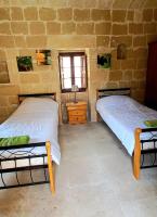 two beds in a room with a brick wall at Ta Majsi farmhouse with indoor heated pool in San Lawrenz