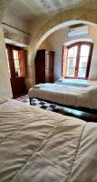 two beds in a room with two windows at Ta Majsi farmhouse with indoor heated pool in San Lawrenz