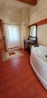 a bathroom with a tub and a sink and a mirror at Ta Majsi farmhouse with indoor heated pool in San Lawrenz