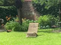 a wooden chair sitting in the grass in a yard at La Maison Saint Joseph in Crépy-en-Valois