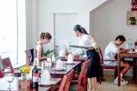 uma mulher a preparar comida numa mesa num restaurante em White Corner Hotel em Phnom Penh