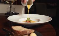 a person pouring mustard into a bowl of soup with bread at Aviator Hampshire in Farnborough