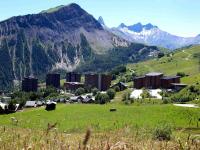 a town in a field with mountains in the background at Studio Pegase Phenix-44 by Interhome in Le Corbier