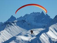 a person riding a parachute over a snow covered mountain at Studio Pegase Phenix-44 by Interhome in Le Corbier